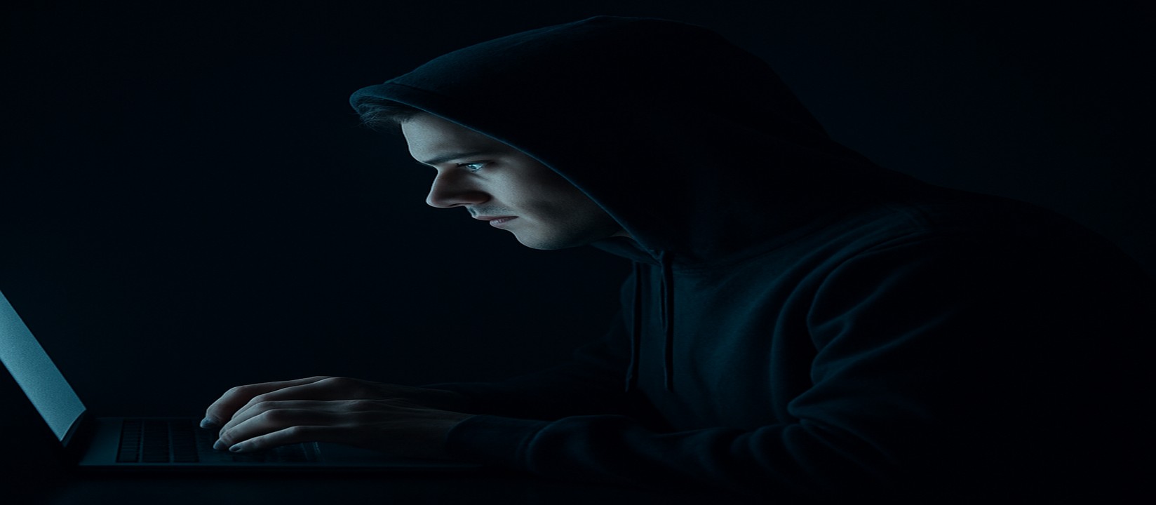 একজন ব্যক্তি অন্ধকারে ল্যাপটপে বসে মনোযোগী চেহারা নিয়ে 89bd-র ওয়েবসাইটে অনলাইন গেমিং করছেন